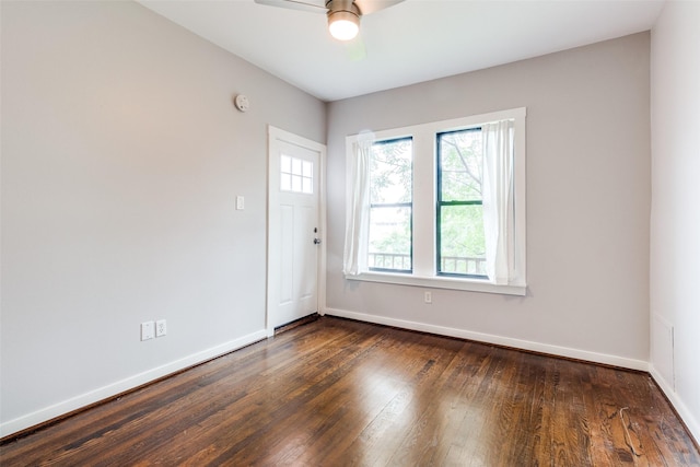 empty room featuring dark wood finished floors, baseboards, and a ceiling fan