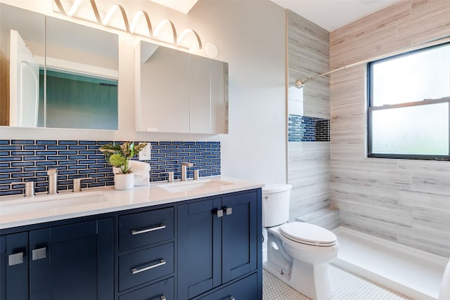 bathroom with toilet, tiled shower, double vanity, and a sink