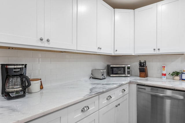 kitchen with light stone countertops, stainless steel appliances, white cabinets, and tasteful backsplash