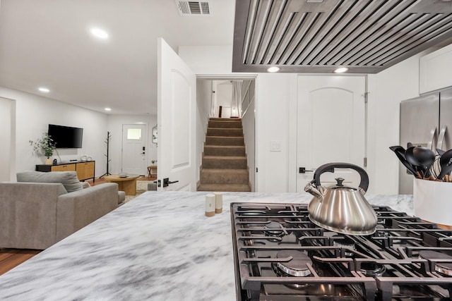 kitchen with open floor plan, visible vents, light stone countertops, premium range hood, and recessed lighting