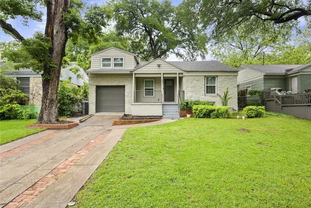 split level home featuring a porch, roof with shingles, an attached garage, driveway, and a front yard