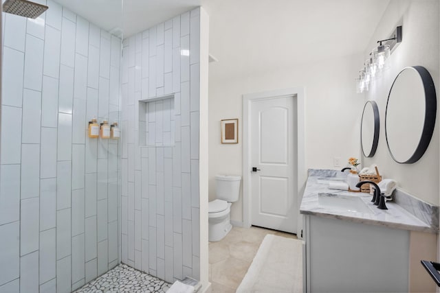 bathroom with vanity, toilet, tile patterned flooring, and a tile shower