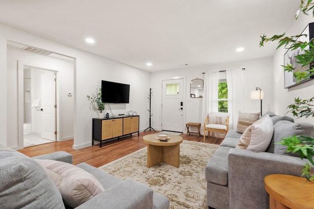 living room with recessed lighting, visible vents, and wood finished floors