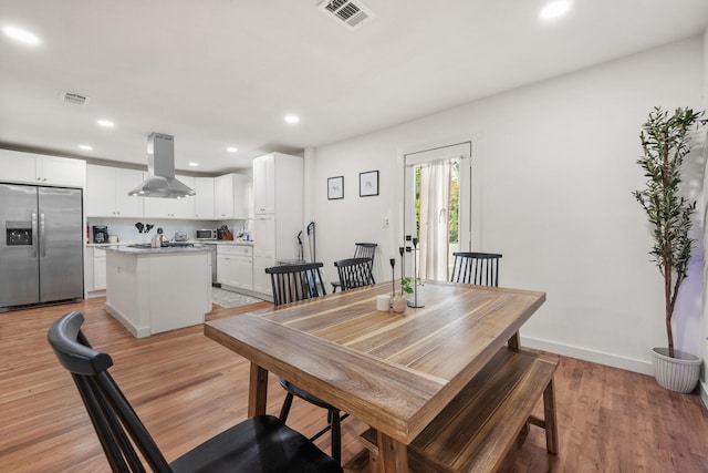 dining space featuring light wood finished floors, baseboards, visible vents, and recessed lighting