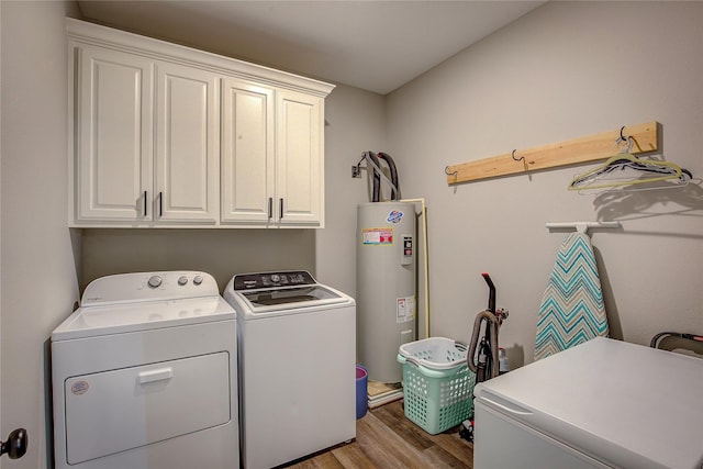 laundry area featuring washing machine and clothes dryer, electric water heater, cabinet space, and wood finished floors