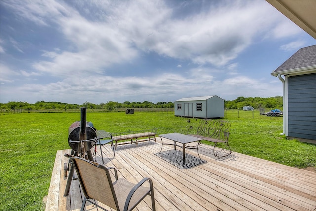 wooden deck featuring a lawn, a rural view, an outbuilding, and a storage shed