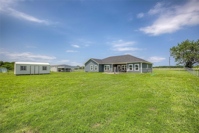 rear view of property featuring a lawn, a shed, an outdoor structure, and fence