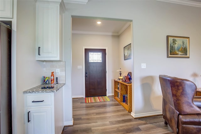 foyer entrance featuring crown molding, wood finished floors, baseboards, and recessed lighting