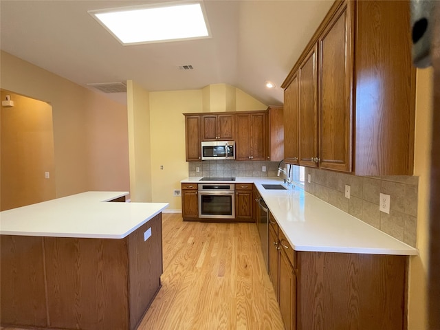 kitchen with light wood-style flooring, brown cabinets, light countertops, appliances with stainless steel finishes, and tasteful backsplash