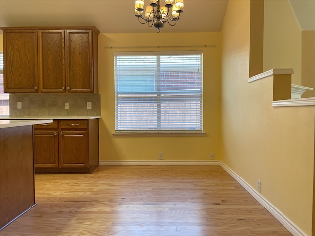 kitchen with an inviting chandelier, light wood-style flooring, light countertops, and brown cabinets