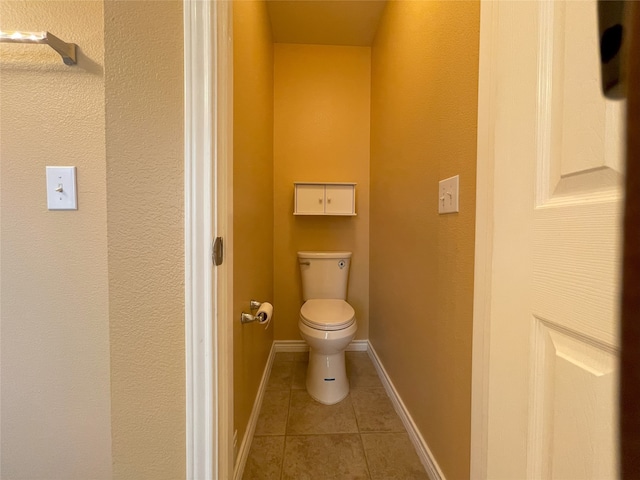 bathroom with toilet, tile patterned flooring, and baseboards