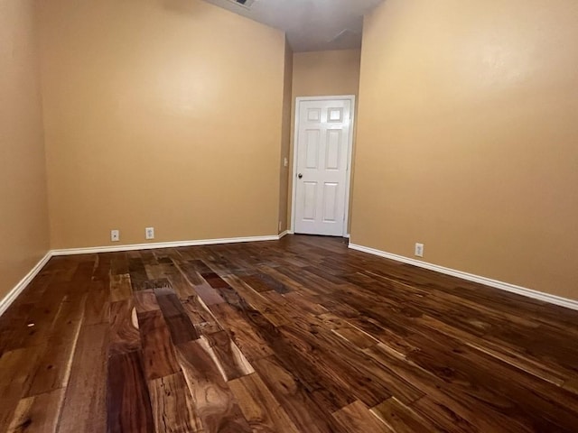 spare room featuring baseboards and dark wood-style floors
