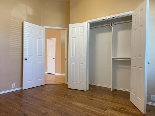 unfurnished bedroom with baseboards, a closet, and wood finished floors
