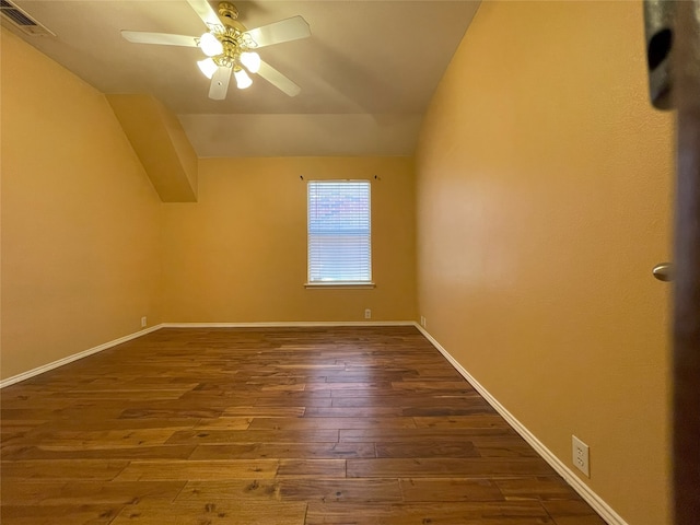 interior space featuring baseboards, dark wood-style flooring, ceiling fan, visible vents, and vaulted ceiling