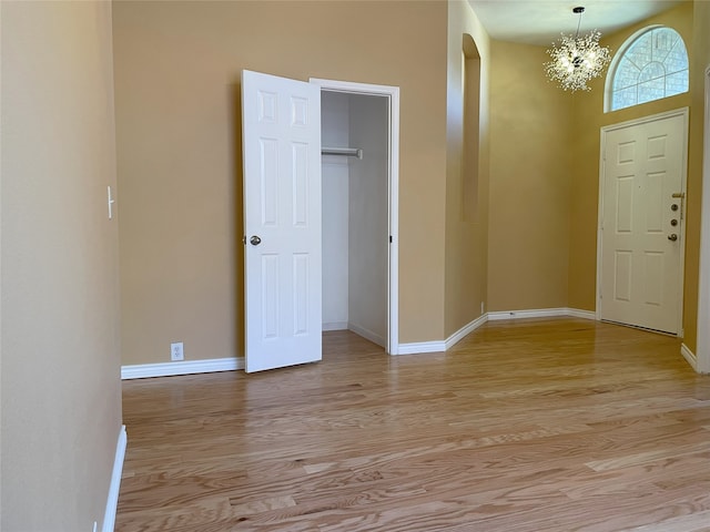 entrance foyer featuring an inviting chandelier, light wood-style flooring, baseboards, and arched walkways