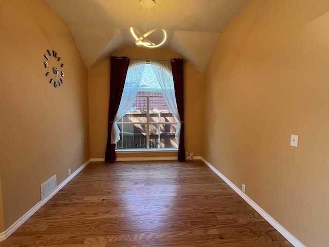 interior space featuring wood finished floors, baseboards, visible vents, vaulted ceiling, and a notable chandelier