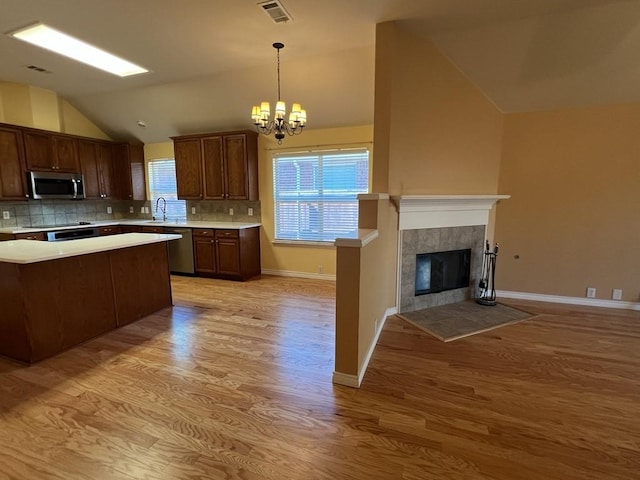 kitchen with light wood-style flooring, visible vents, a sink, vaulted ceiling, and stainless steel appliances