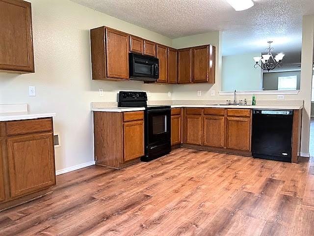 714 Kinston Ct, Wylie, TX 75098 - kitchen with a chandelier, light countertops, black appliances, and light wood-style floors