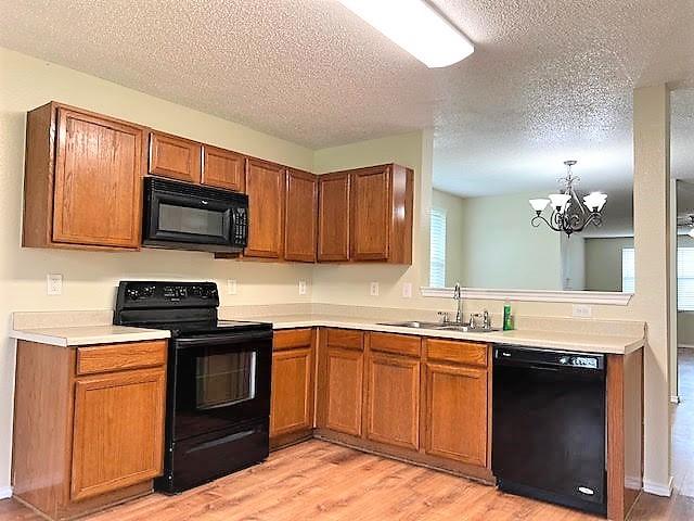 714 Kinston Ct, Wylie, TX 75098 - kitchen with light wood finished floors, a sink, brown cabinets, black appliances, and light countertops