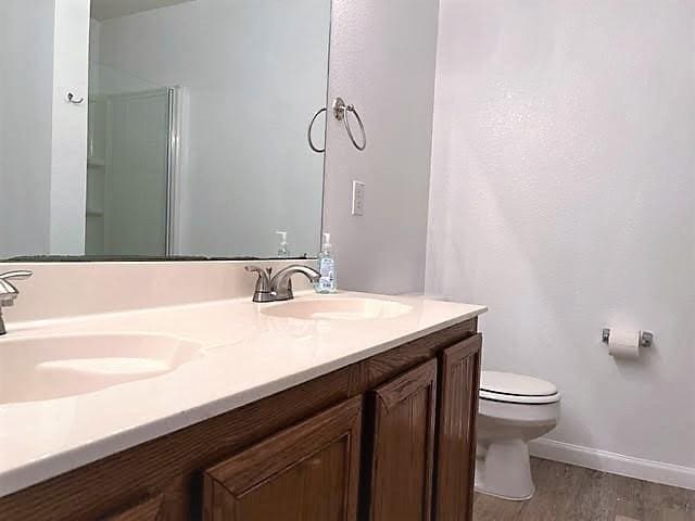 714 Kinston Ct, Wylie, TX 75098 - bathroom featuring double vanity, toilet, wood finished floors, and a sink