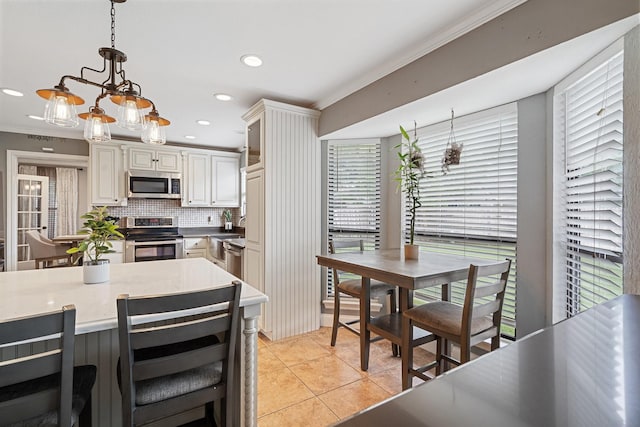 kitchen featuring stainless steel appliances, decorative light fixtures, decorative backsplash, light tile patterned flooring, and ornamental molding