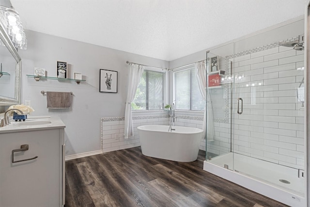 full bath with vanity, wood finished floors, a shower stall, and a freestanding tub
