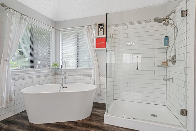 bathroom featuring a stall shower, a soaking tub, a textured ceiling, and wood finished floors