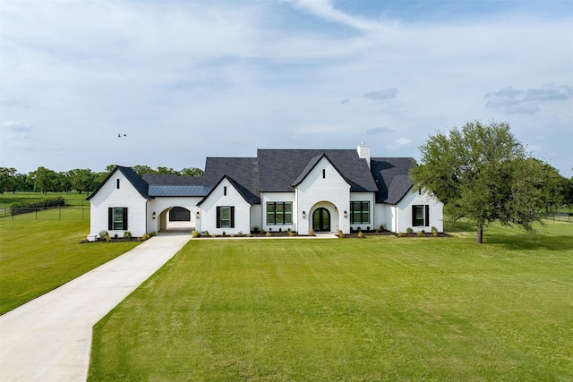 view of front of home with stucco siding, a chimney, fence, concrete driveway, and a front yard