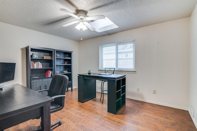 2605 Nighthawk Dr, Plano, TX 75025 - home office with wood finished floors, a ceiling fan, a skylight, a textured ceiling, and baseboards