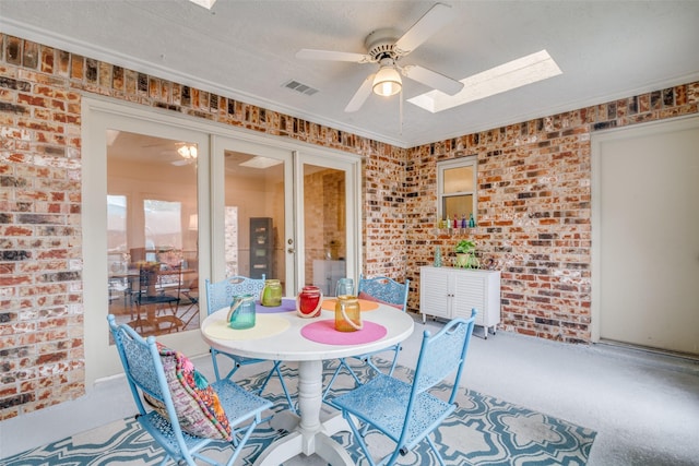 2605 Nighthawk Dr, Plano, TX 75025 - dining room featuring brick wall, a skylight, a ceiling fan, and visible vents