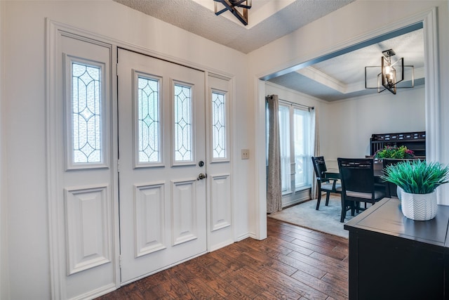 2605 Nighthawk Dr, Plano, TX 75025 - entrance foyer with dark wood finished floors, an inviting chandelier, crown molding, and a textured ceiling