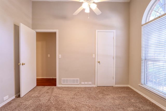 spare room with carpet flooring, visible vents, a ceiling fan, and a healthy amount of sunlight