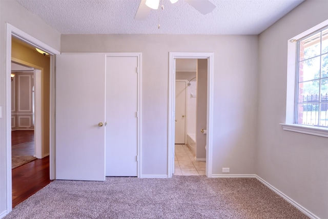 unfurnished bedroom featuring light colored carpet, a textured ceiling, and baseboards