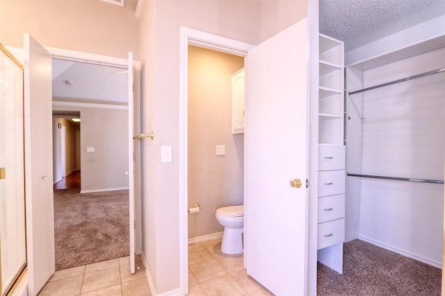 full bath with toilet, baseboards, tile patterned flooring, and a walk in closet