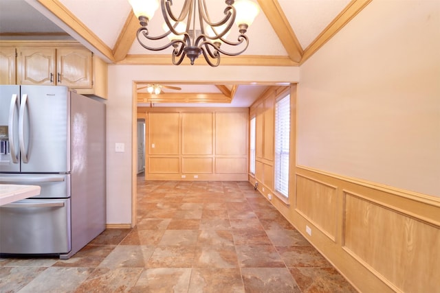 kitchen featuring lofted ceiling, a decorative wall, ceiling fan with notable chandelier, stone finish floor, and stainless steel fridge