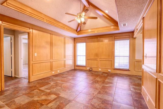 empty room featuring a decorative wall, a ceiling fan, and a healthy amount of sunlight