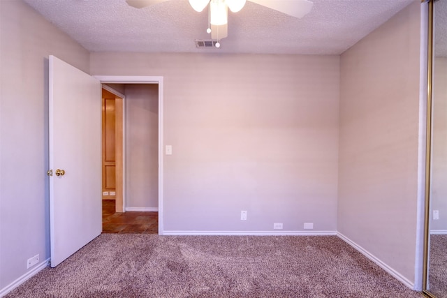 unfurnished room featuring ceiling fan, a textured ceiling, carpet flooring, and visible vents