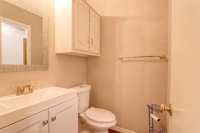 bathroom with toilet, baseboards, and vanity