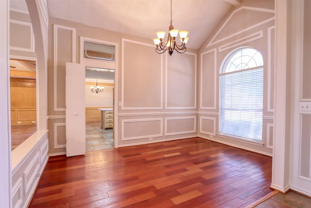 unfurnished dining area featuring lofted ceiling, a decorative wall, an inviting chandelier, and dark wood-style floors