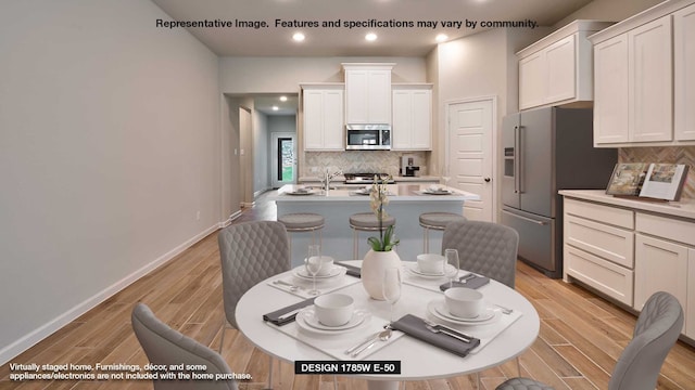 dining area featuring baseboards, light wood-style floors, and recessed lighting