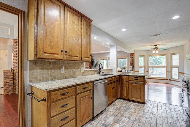 kitchen featuring stainless steel appliances, a sink, a ceiling fan, brown cabinetry, and recessed lighting