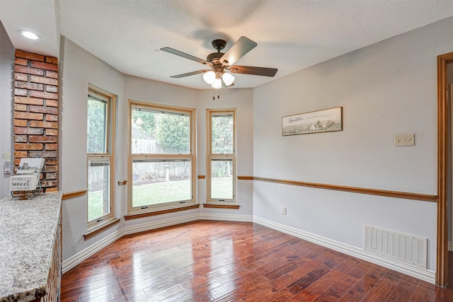 unfurnished room featuring ceiling fan, baseboards, wood finished floors, plenty of natural light, and a textured ceiling