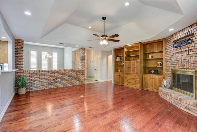 unfurnished living room featuring a large fireplace, wood finished floors, a ceiling fan, a raised ceiling, and recessed lighting