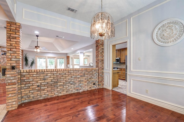 unfurnished dining area with ceiling fan, hardwood / wood-style floors, a chandelier, and a tray ceiling