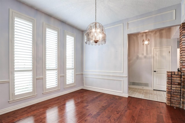 unfurnished dining area featuring a chandelier, hardwood / wood-style floors, and baseboards