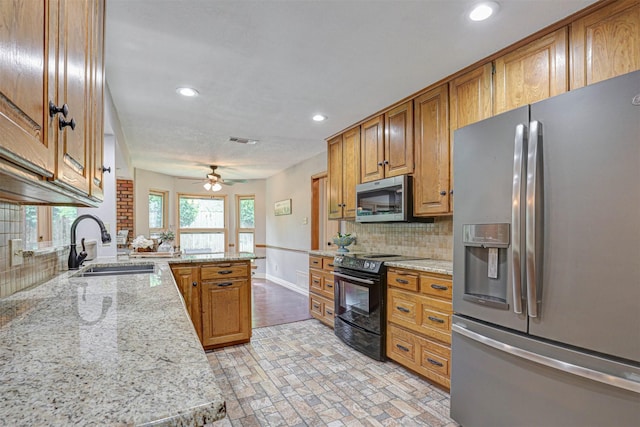 kitchen featuring stainless steel appliances, a sink, a peninsula, recessed lighting, and tasteful backsplash