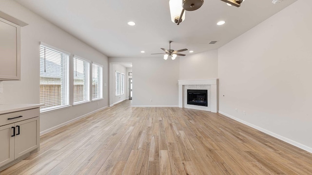 122 Palo Duro Bnd, Rhome, TX 76078 - unfurnished living room featuring a ceiling fan, a glass covered fireplace, light wood-type flooring, and recessed lighting