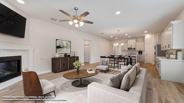 122 Palo Duro Bnd, Rhome, TX 76078 - living area with light wood-style flooring, ceiling fan, a fireplace, a chandelier, and recessed lighting