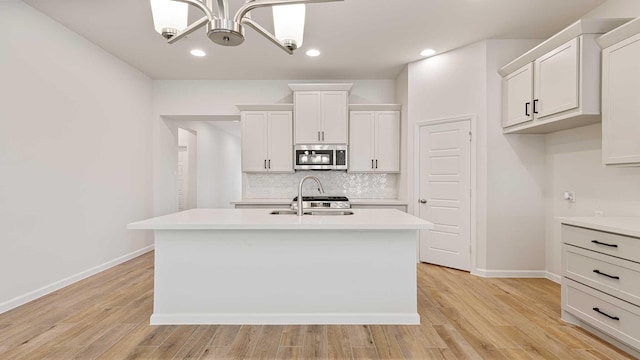 122 Palo Duro Bnd, Rhome, TX 76078 - kitchen featuring stainless steel microwave, light countertops, decorative backsplash, a center island with sink, and recessed lighting