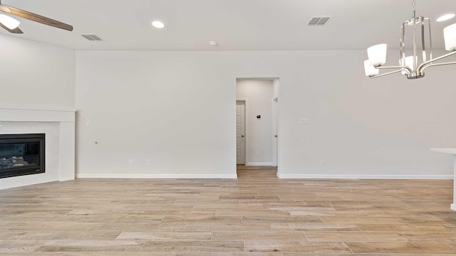 122 Palo Duro Bnd, Rhome, TX 76078 - unfurnished living room with a chandelier, light wood-style flooring, a glass covered fireplace, ceiling fan, and recessed lighting